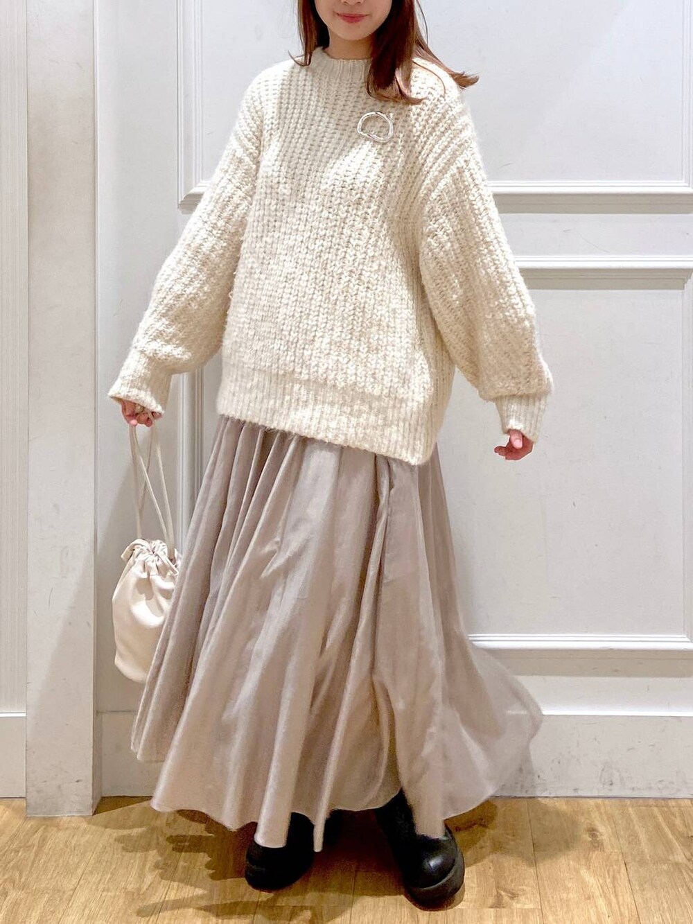 ホワイト系のショルダーバッグ、ホワイト系のニット/セーター、ブラック系のブーツを着用したレディースの春コーディネートの5枚目の写真