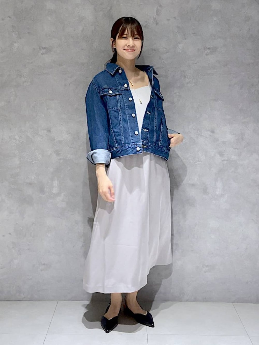 ブルー系のデニムジャケット、グレー系のドレス、ブラック系のパンプスを着用したレディースの秋コーディネートの3枚目の写真
