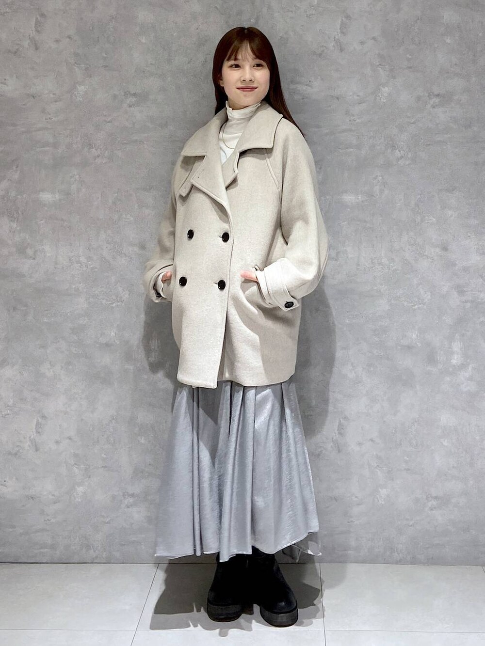 ベージュ系のピーコート、ホワイト系のTシャツ/カットソー、ブラック系のブーツを着用したレディースの冬コーディネートの3枚目の写真