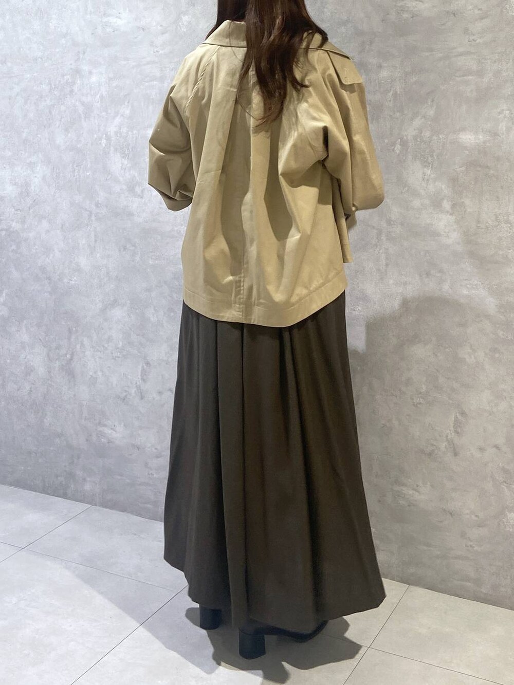 ブラウン系のジャンパースカート、ブラック系のショルダーバッグ、ベージュ系のトレンチコートを着用したレディースの秋コーディネートの6枚目の写真