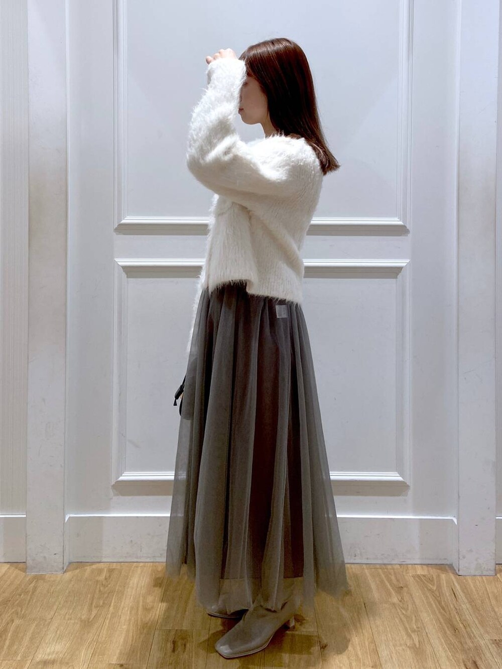 ホワイト系のカーディガン/ボレロ、ホワイト系のブーツ、ブラック系のショルダーバッグを着用したレディースの冬コーディネートの3枚目の写真