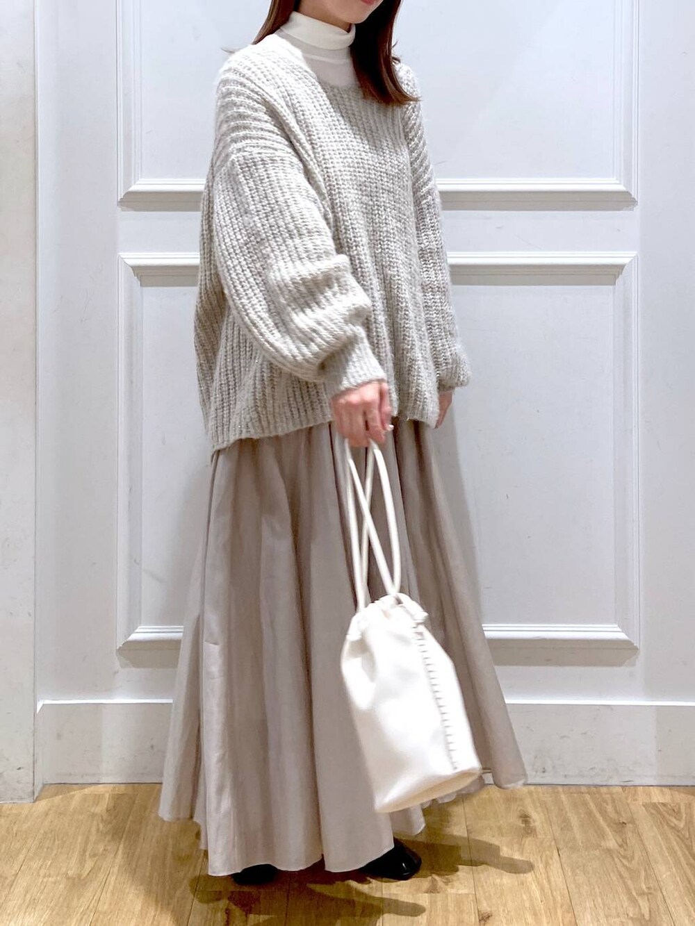 ホワイト系のショルダーバッグ、ベージュ系のスカート、ブラック系のブーツを着用したレディースの冬コーディネートの4枚目の写真