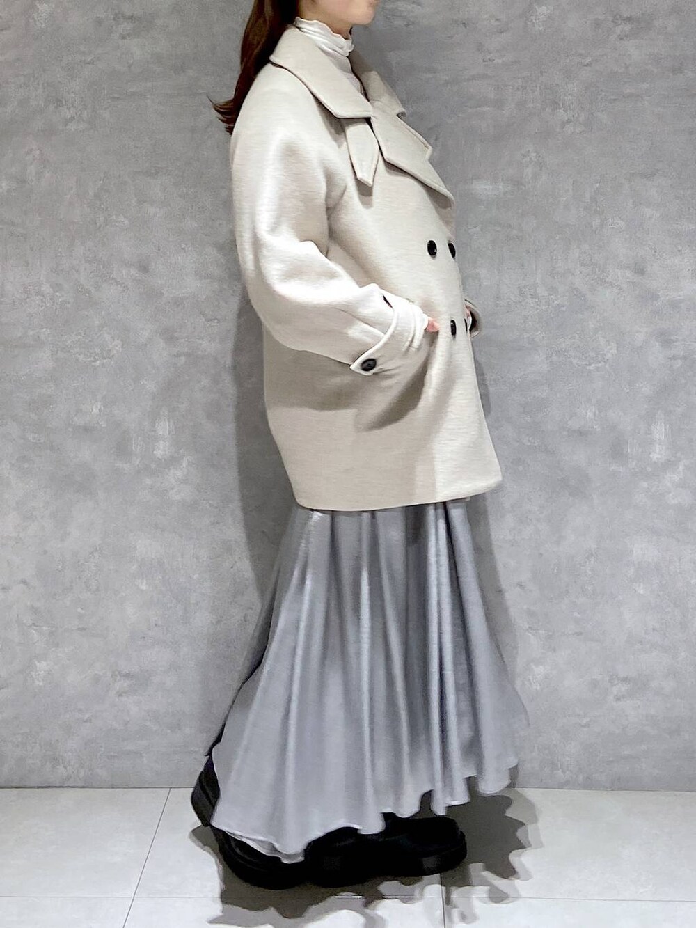 ベージュ系のピーコート、ホワイト系のTシャツ/カットソー、ブラック系のブーツを着用したレディースの冬コーディネートの4枚目の写真