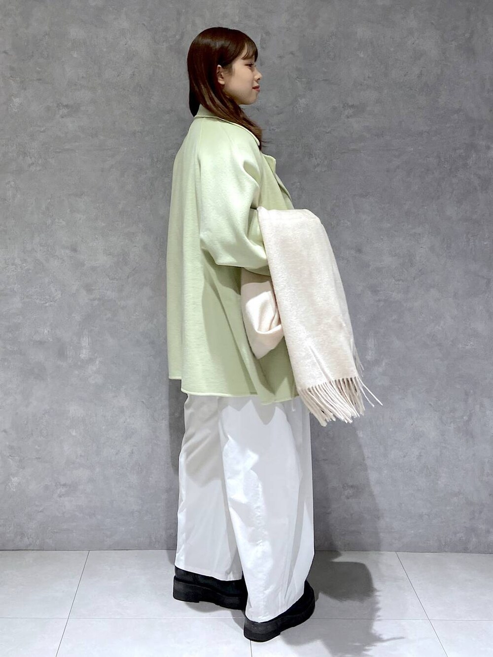 グリーン系のその他アウター、ホワイト系のニット/セーター、ブラック系のブーツを着用したレディースの冬コーディネートの5枚目の写真