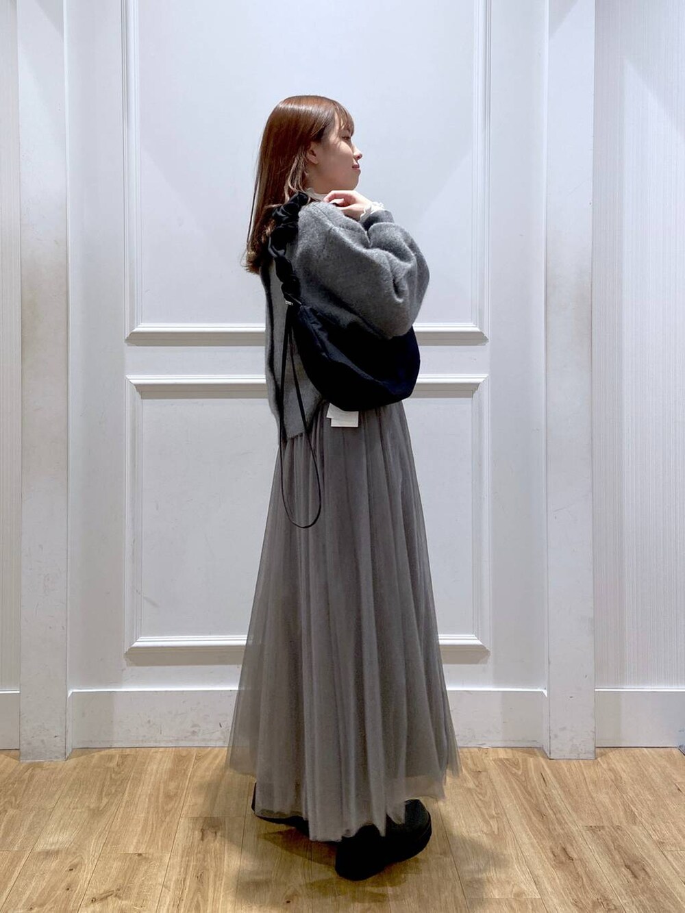 ホワイト系のTシャツ/カットソー、グレー系のカーディガン/ボレロ、ブラック系のブーツを着用したレディースの冬コーディネートの5枚目の写真