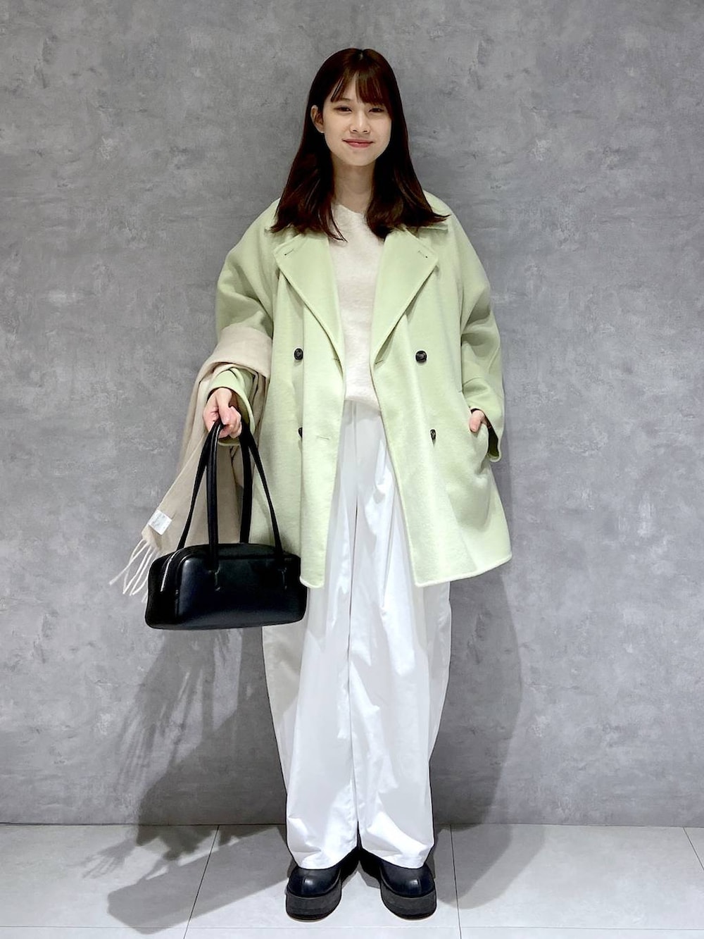 グリーン系のその他アウター、ホワイト系のニット/セーター、ブラック系のブーツを着用したレディースの冬コーディネートの2枚目の写真