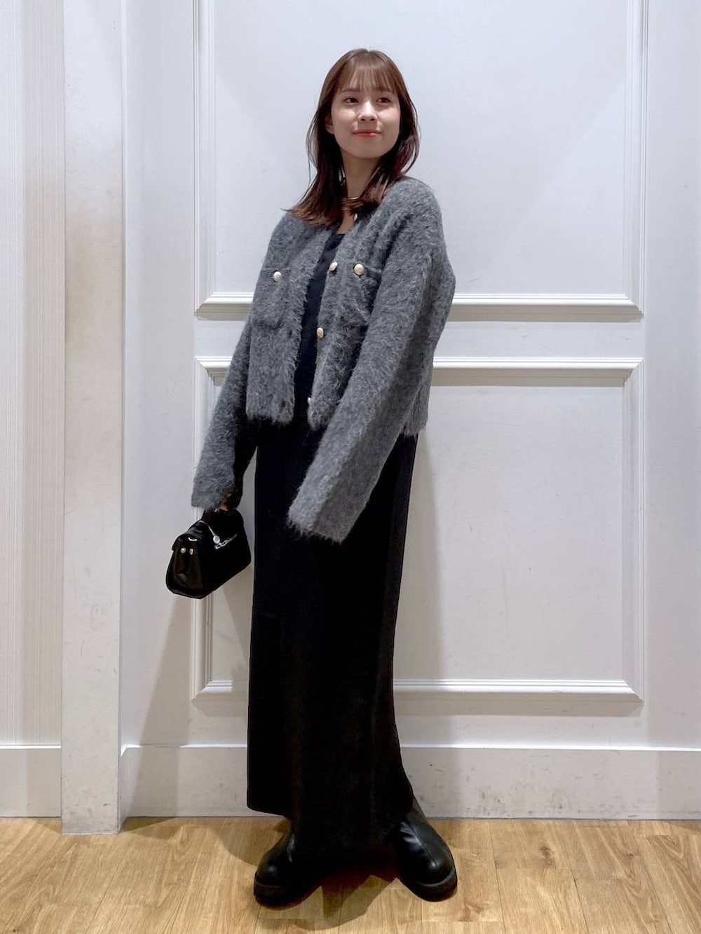 グレー系のカーディガン/ボレロ、ホワイト系のワンピース、ブラック系のショルダーバッグを着用したレディースの冬コーディネートの2枚目の写真