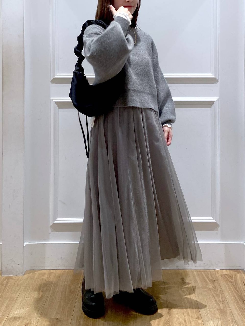 ホワイト系のTシャツ/カットソー、グレー系のカーディガン/ボレロ、ブラック系のブーツを着用したレディースの冬コーディネートの7枚目の写真