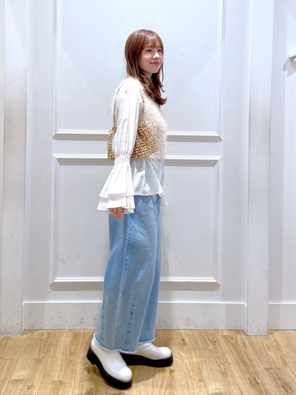 ホワイト系のブーツ、ブルー系のデニムパンツ、ゴールド系のショルダーバッグを着用したレディースの冬コーディネートの3枚目の写真