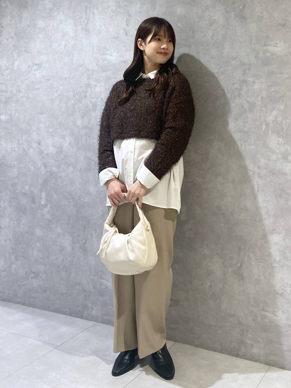 ホワイト系のシャツ/ブラウス、ホワイト系のハンドバッグ、ベージュ系のスラックスを着用したレディースの秋コーディネートの3枚目の写真