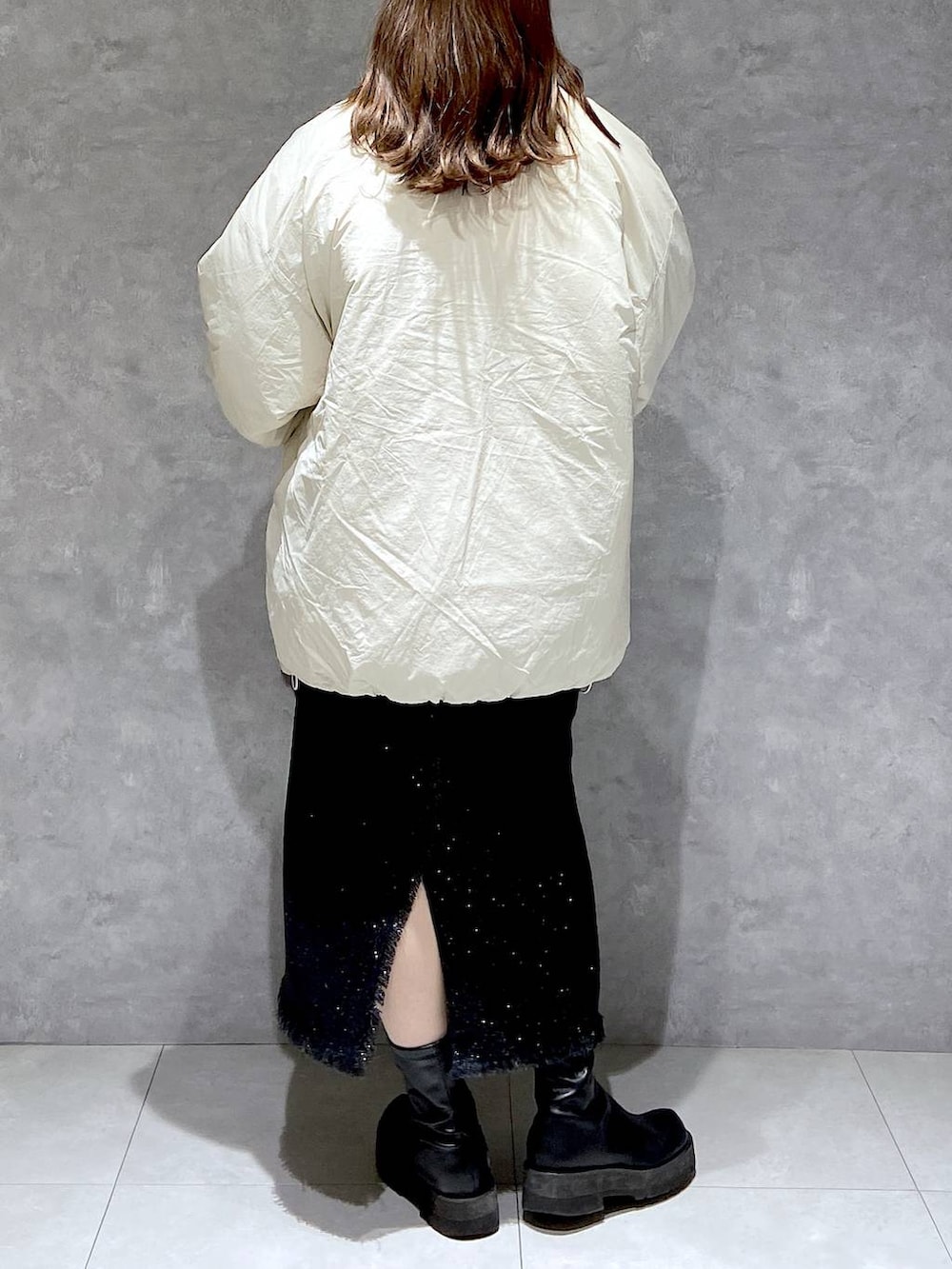 ホワイト系のダウンジャケット/コート、グレー系のスカート、ブラック系のブーツを着用したレディースの冬コーディネートの6枚目の写真