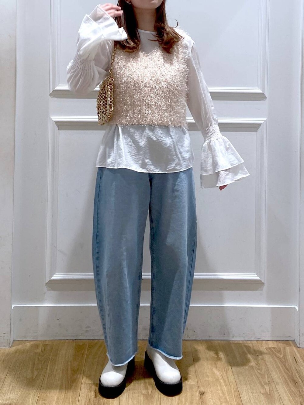 ホワイト系のブーツ、ブルー系のデニムパンツ、ゴールド系のショルダーバッグを着用したレディースの冬コーディネートの5枚目の写真