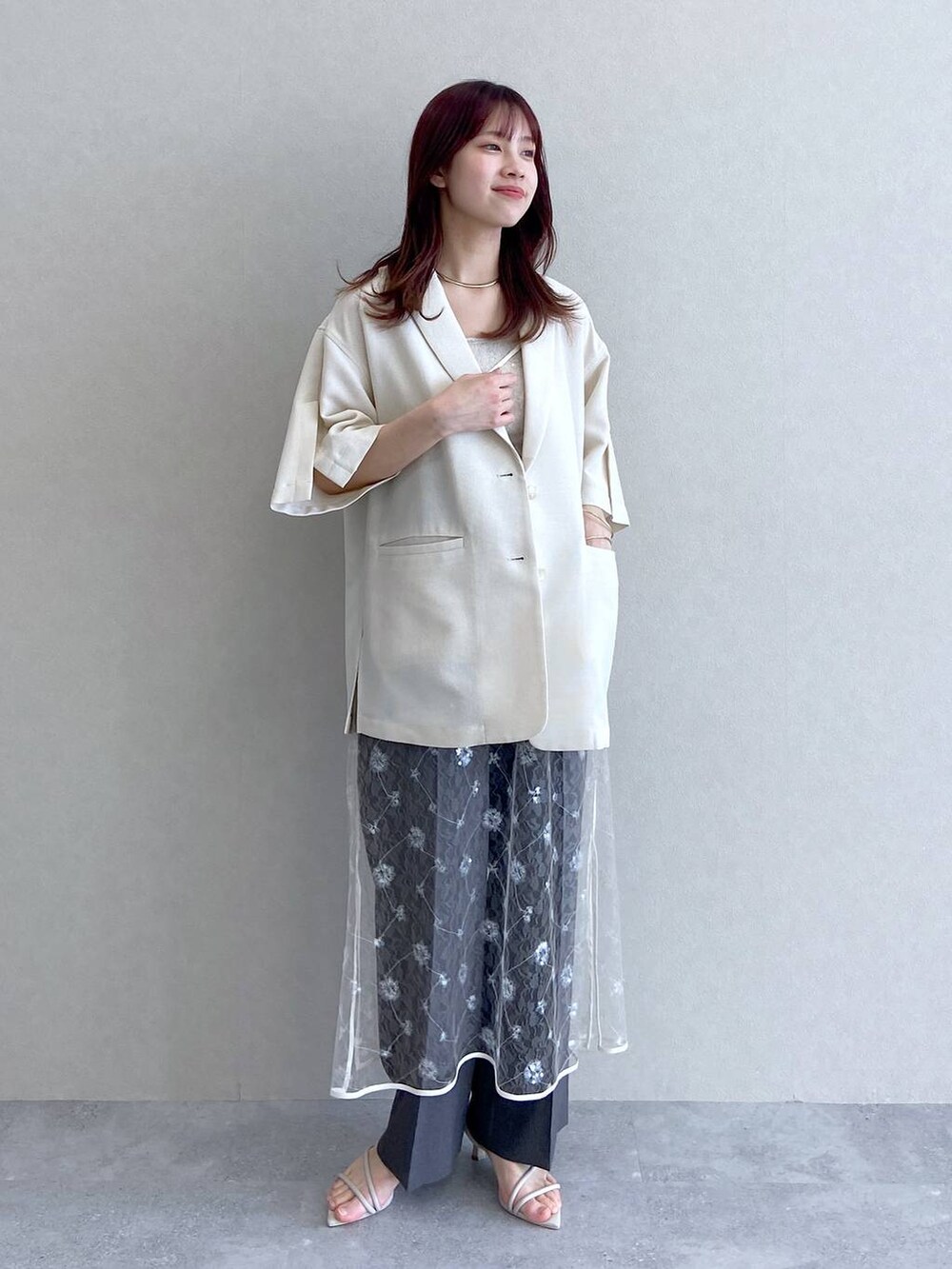 ホワイト系のサンダル、ベージュ系のキャミソール、ホワイト系のテーラードジャケットを着用したレディースの春コーディネートの2枚目の写真