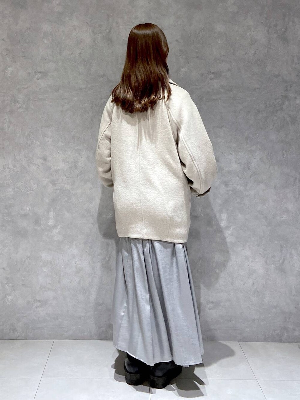 ベージュ系のピーコート、ホワイト系のTシャツ/カットソー、ブラック系のブーツを着用したレディースの冬コーディネートの6枚目の写真