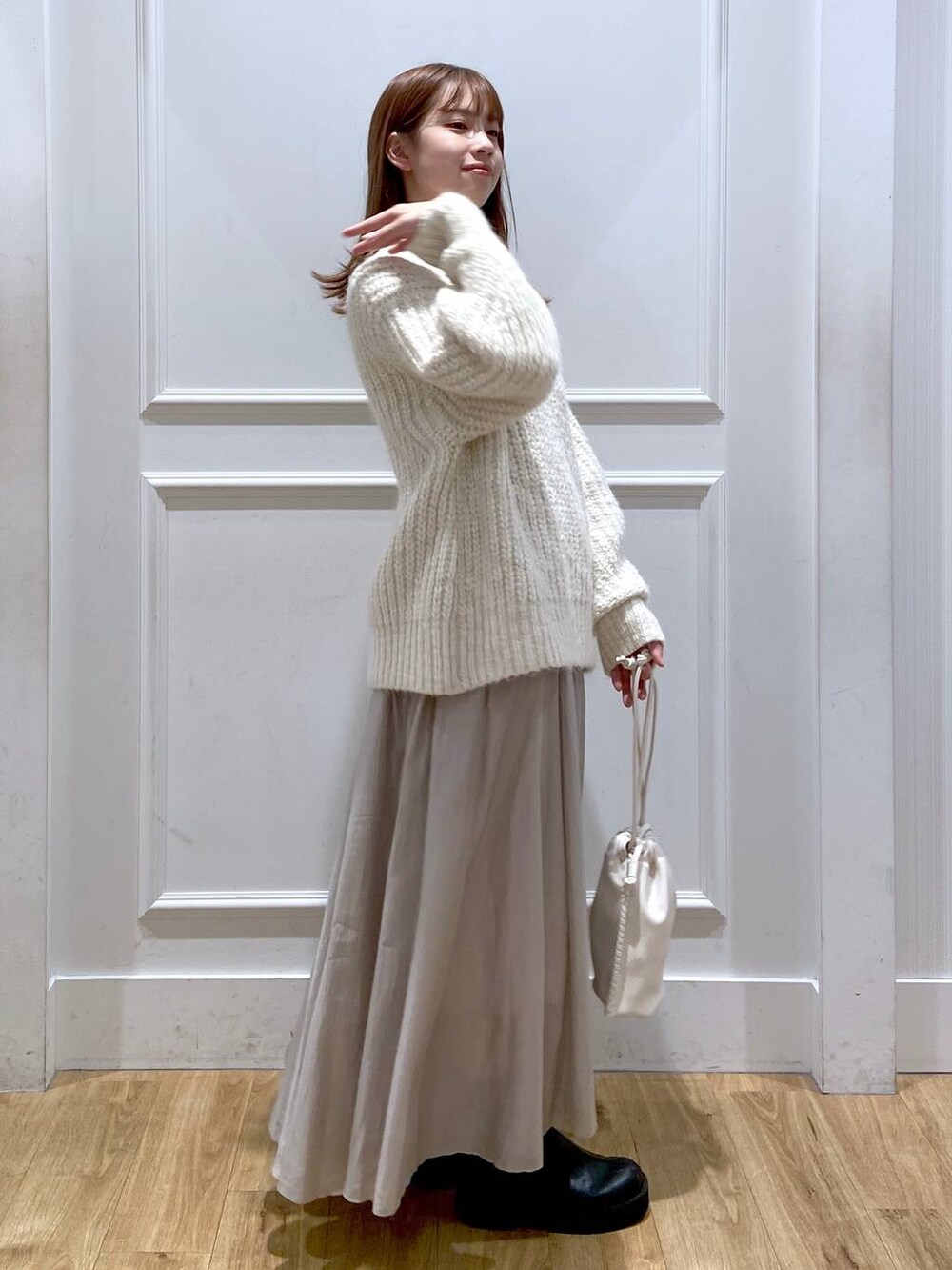 ホワイト系のショルダーバッグ、ホワイト系のニット/セーター、ブラック系のブーツを着用したレディースの春コーディネートの3枚目の写真