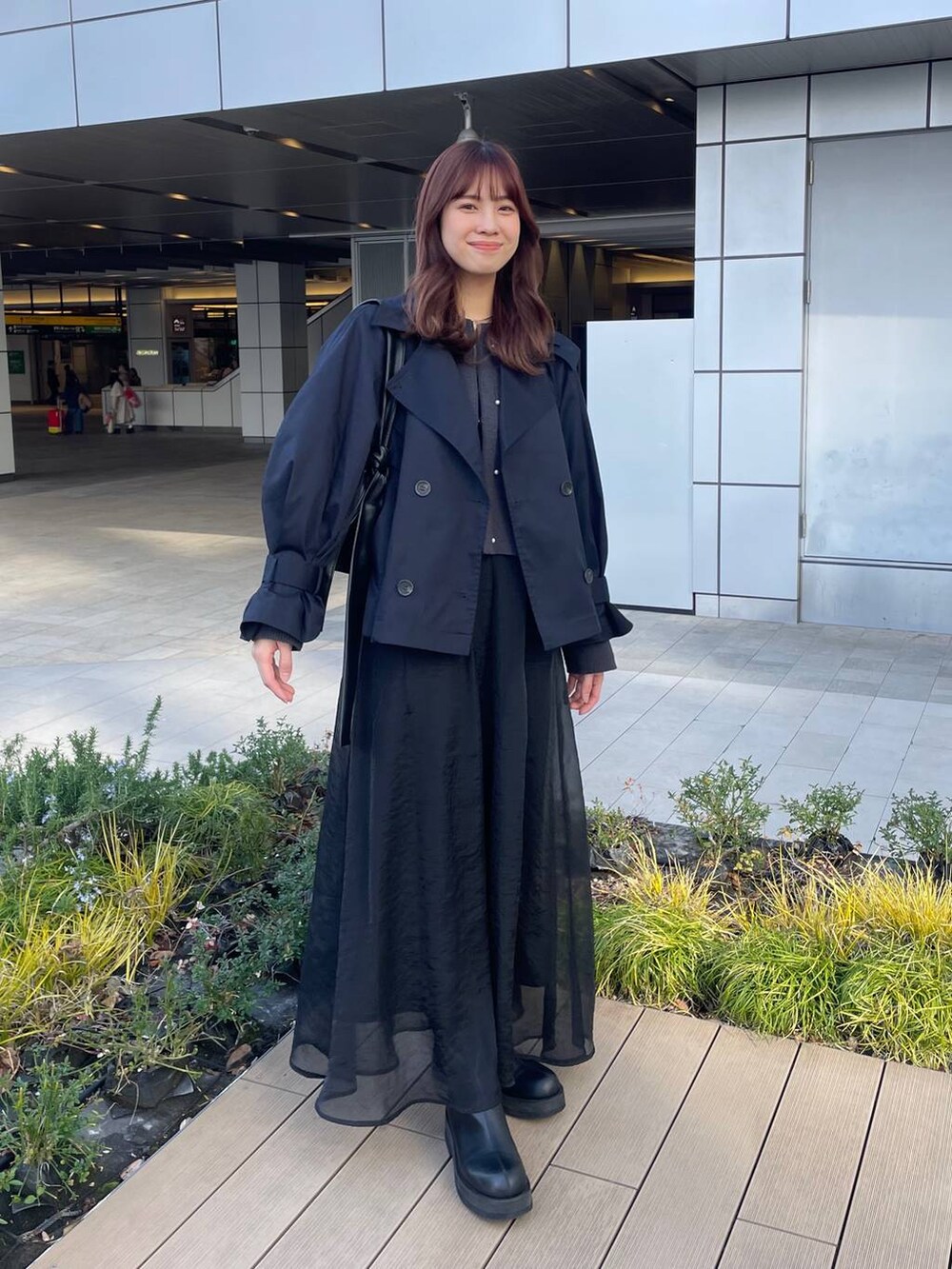 ブラック系のショルダーバッグ、ブルー系のトレンチコート、グレー系のカーディガン/ボレロを着用したレディースの春コーディネートの5枚目の写真