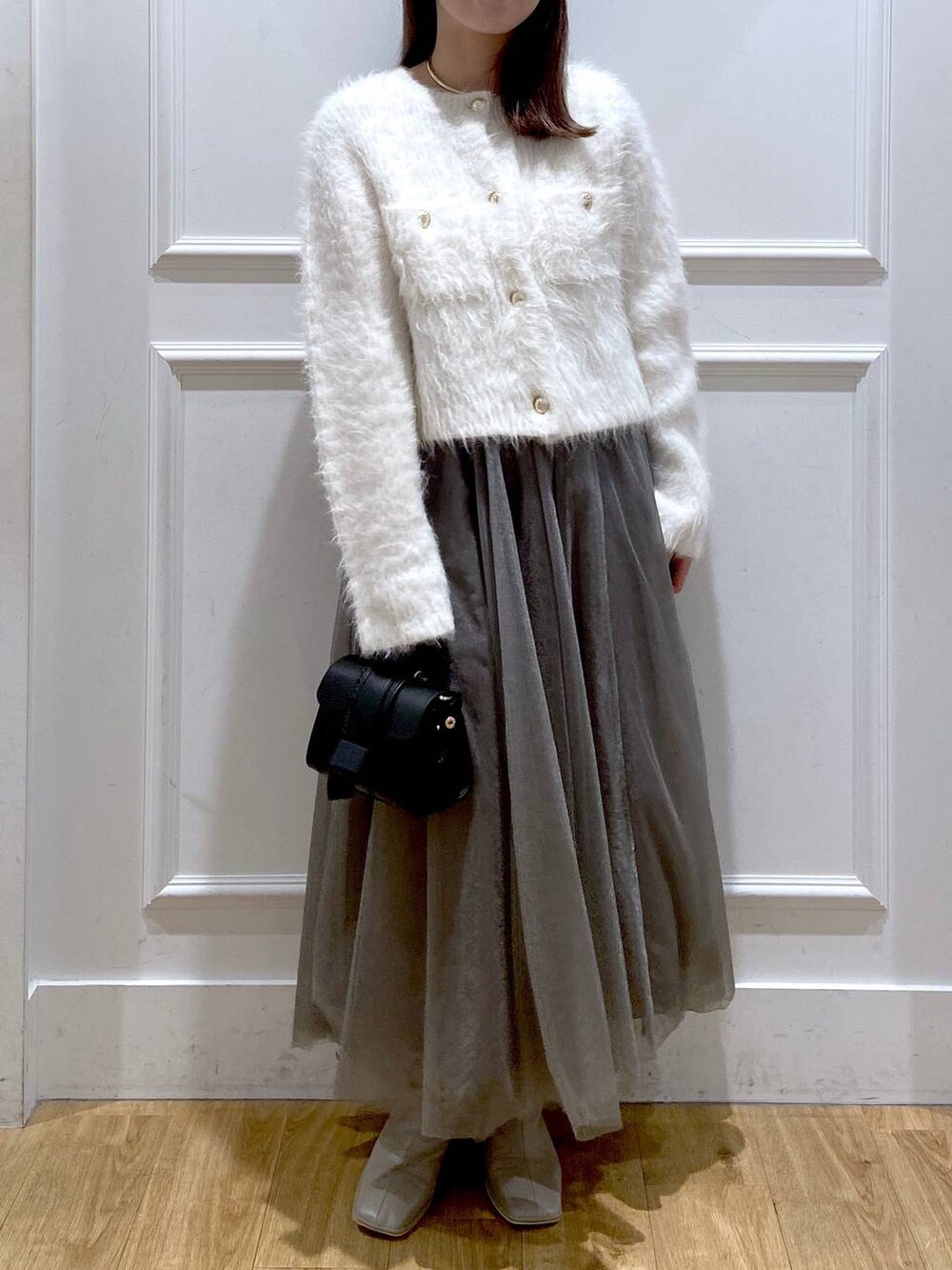 ホワイト系のカーディガン/ボレロ、ホワイト系のブーツ、ブラック系のショルダーバッグを着用したレディースの冬コーディネートの5枚目の写真