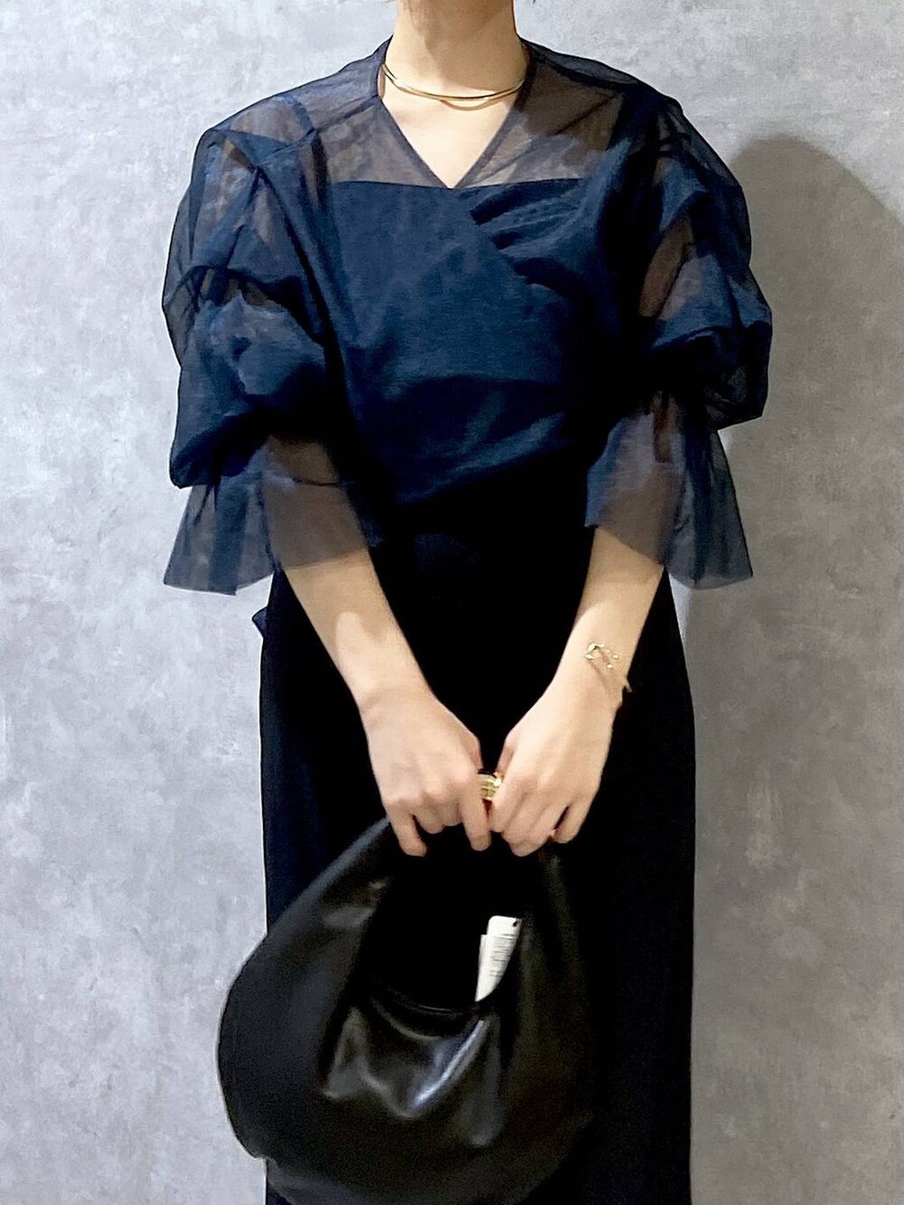 ブラック系のハンドバッグ、ブラック系のパンプス、ブルー系のドレスを着用したレディースの秋コーディネートの6枚目の写真