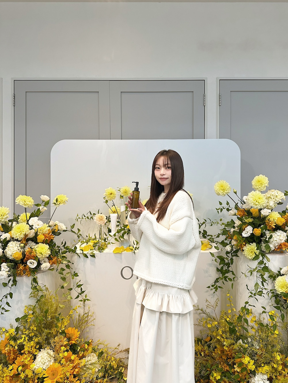 ホワイト系のニット/セーター、ベージュ系のスカート、ブラウン系のブーツを着用したレディースの秋コーディネートの2枚目の写真