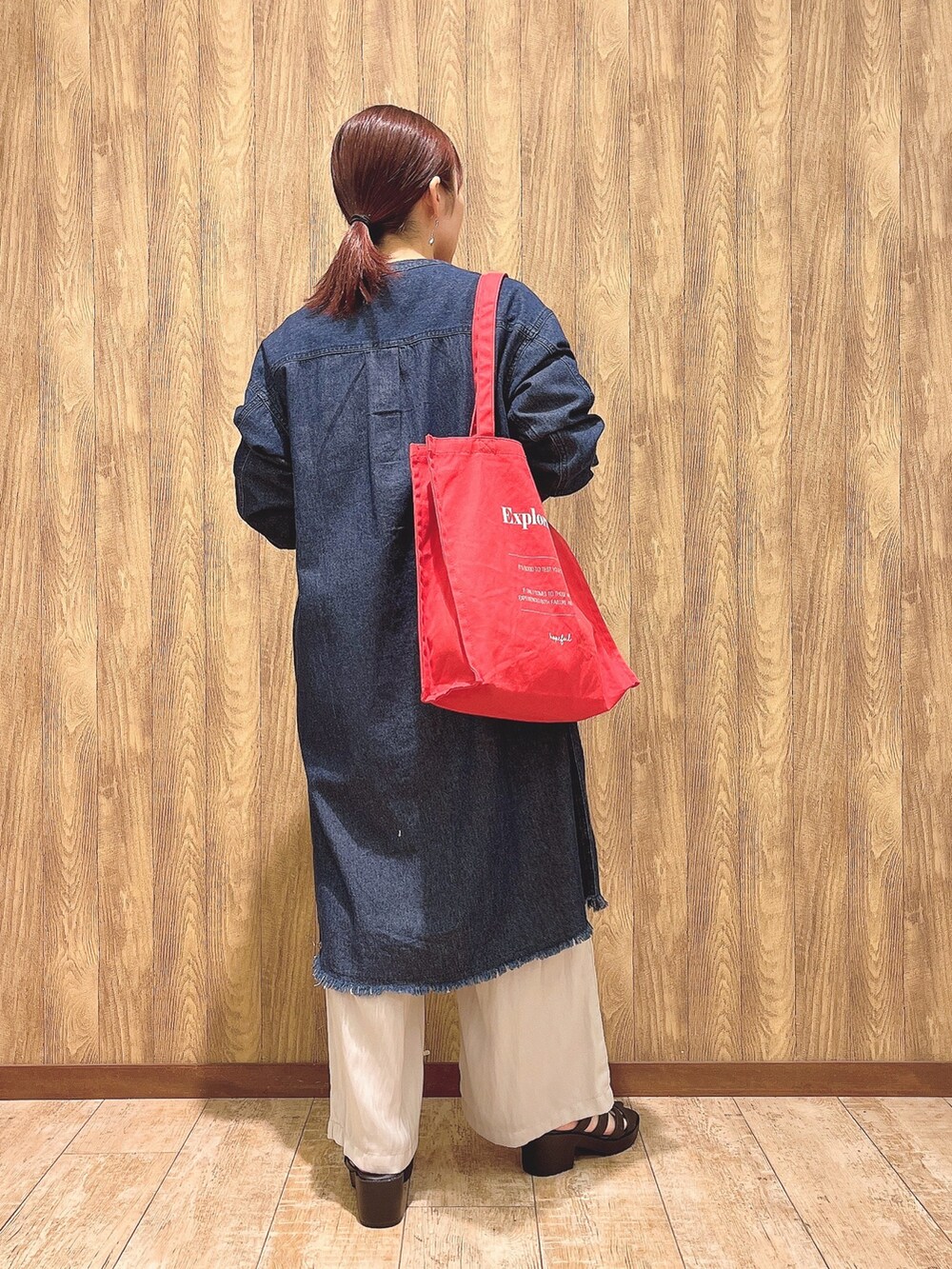 レッド系のトートバッグ、ブルー系のワンピース、グレー系のその他パンツを着用したレディースの春コーディネートの3枚目の写真