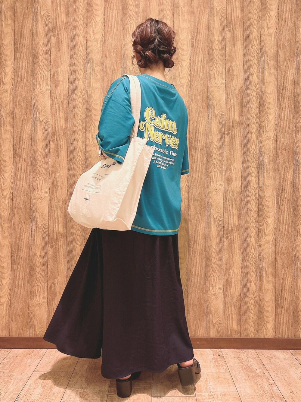 グリーン系のTシャツ/カットソー、ブルー系のスカート、ホワイト系のトートバッグを着用したレディースの春コーディネートの3枚目の写真