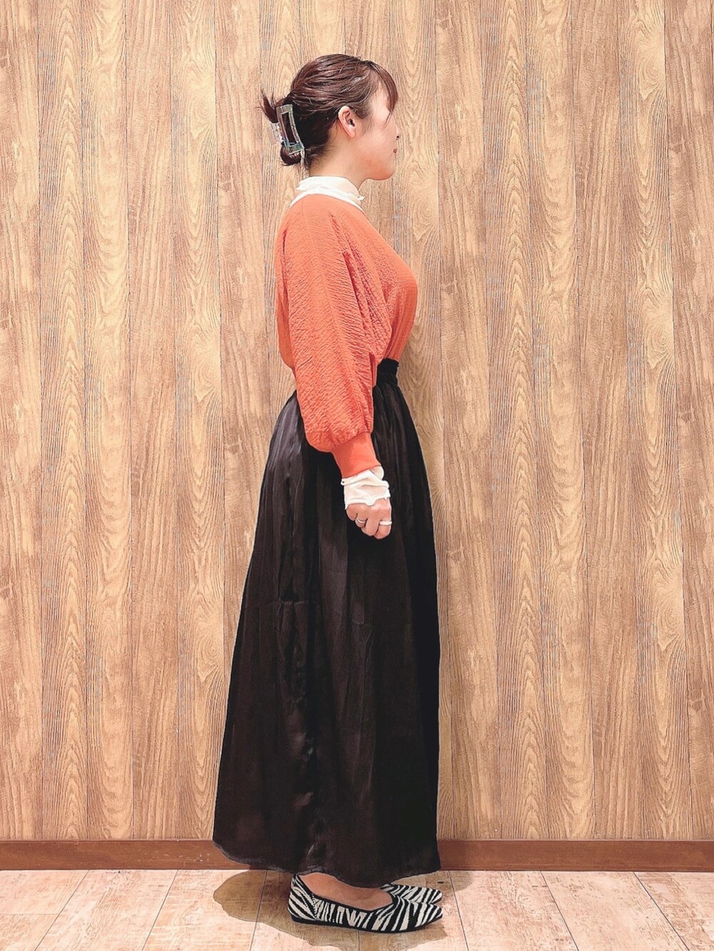 オレンジ系のシャツ/ブラウス、ベージュ系のTシャツ/カットソー、グレー系のスカートを着用したレディースの春コーディネートの2枚目の写真