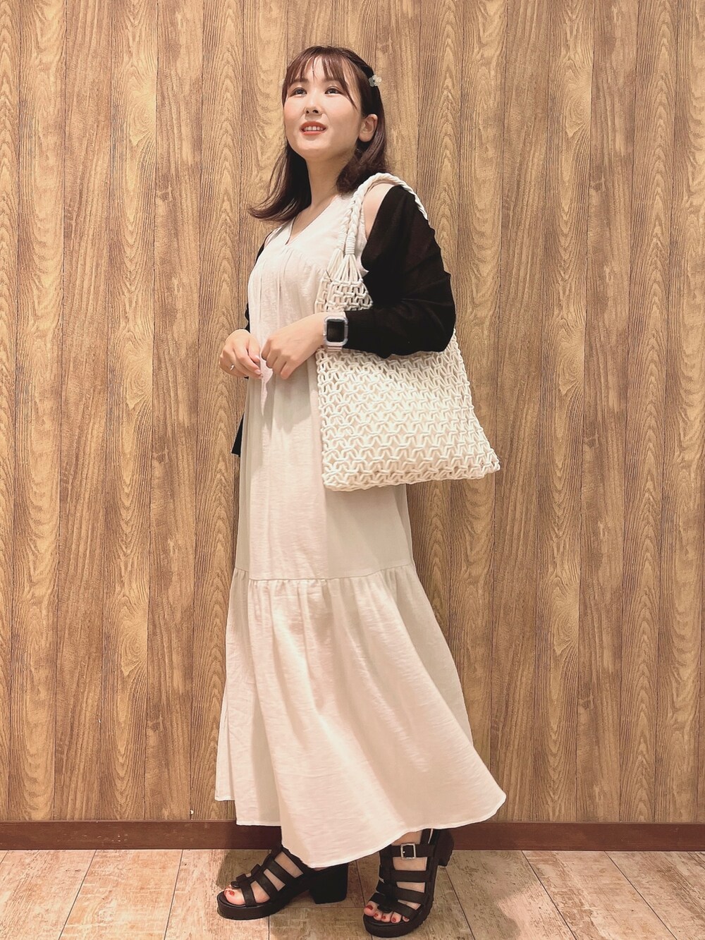 ブラック系のカーディガン/ボレロ、ベージュ系のワンピース、ブラック系のサンダルを着用したレディースの夏コーディネートの2枚目の写真