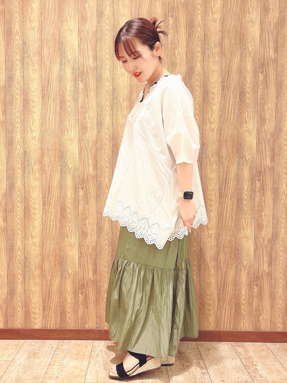 グリーン系のスカート、ブラック系のサンダル、ホワイト系のシャツ/ブラウスを着用したレディースの春コーディネートの2枚目の写真