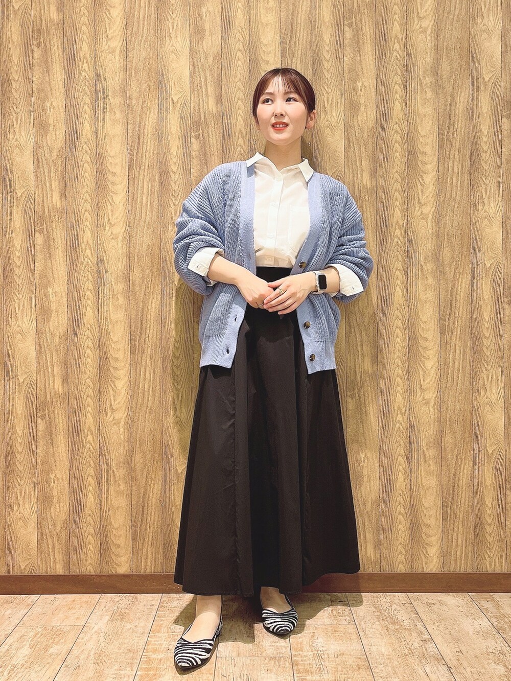 ホワイト系のシャツ/ブラウス、ブルー系のカーディガン/ボレロ、ブラック系のスカートを着用したレディースの春コーディネートの2枚目の写真