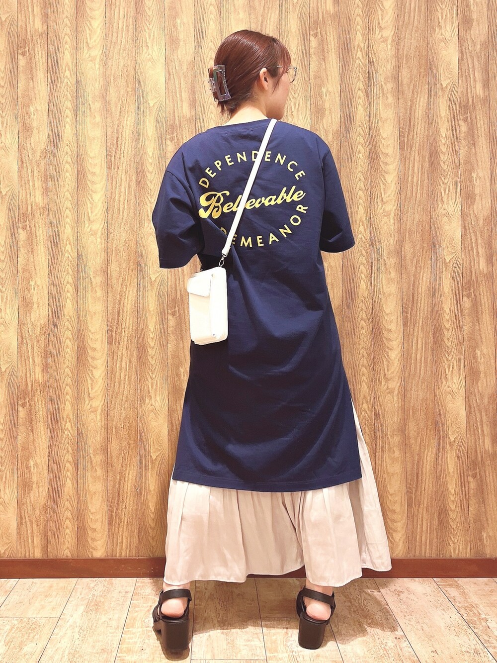 ブルー系のチュニック、ベージュ系のスカート、ホワイト系のショルダーバッグを着用したレディースの春コーディネートの2枚目の写真