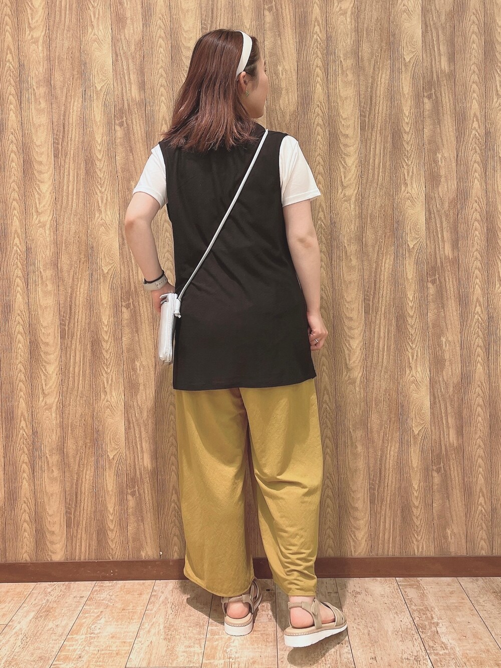 イエロー系のその他パンツ、ベージュ系のサンダル、ブラック系のベストを着用したレディースの夏コーディネートの3枚目の写真