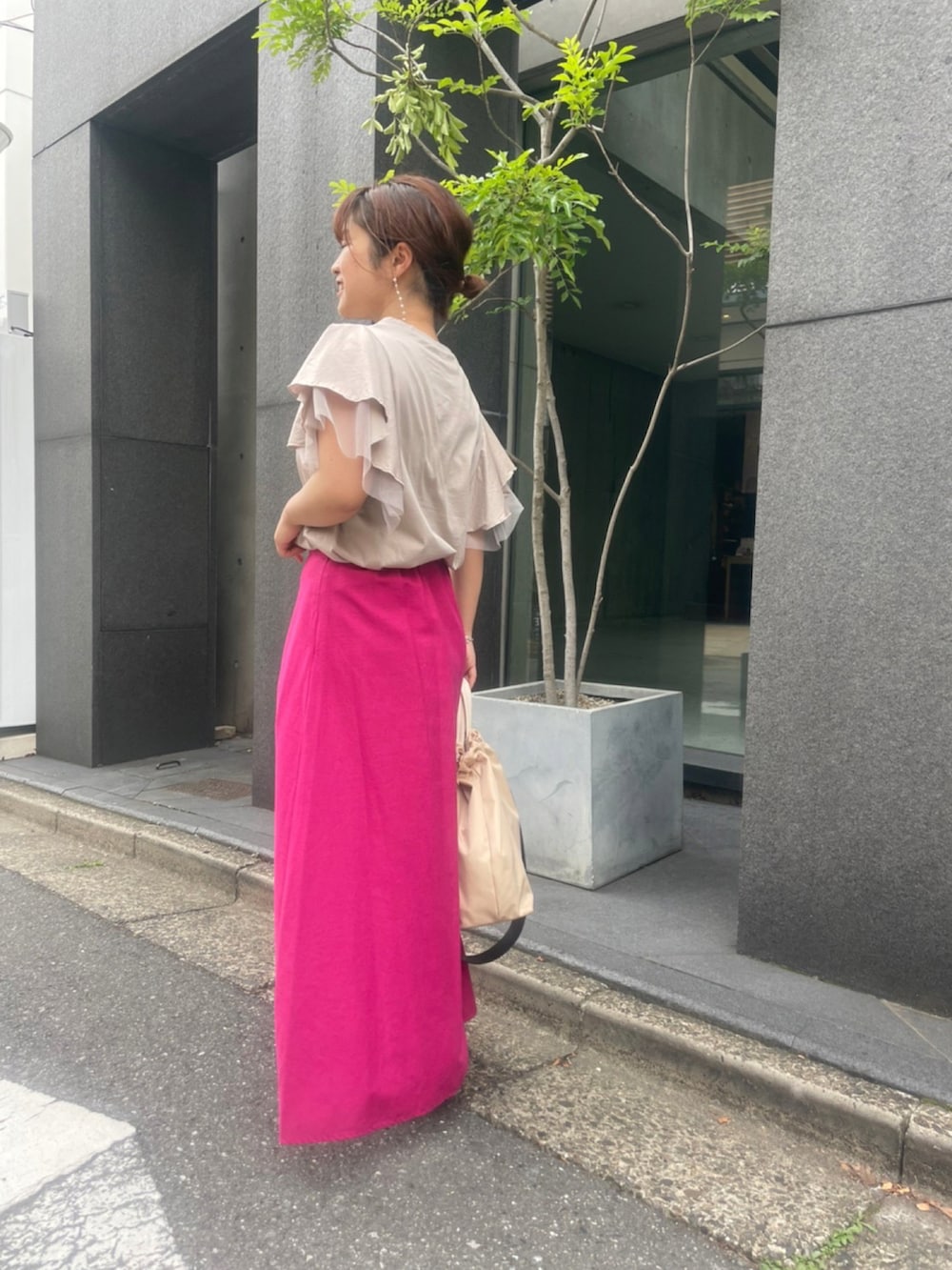 ベージュ系のTシャツ/カットソー、ピンク系のスカート、ベージュ系のショルダーバッグを着用したレディースの春コーディネートの4枚目の写真
