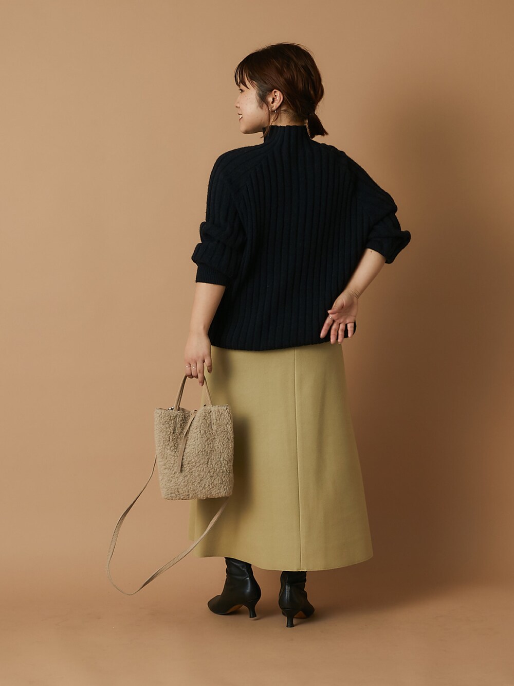 ベージュ系のショルダーバッグ、ブラック系のニット/セーター、イエロー系のスカートを着用したレディースの冬コーディネートの3枚目の写真