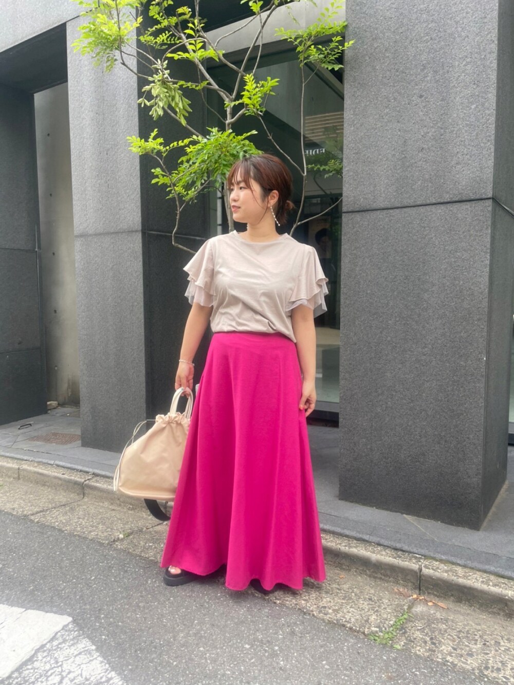 ベージュ系のTシャツ/カットソー、ピンク系のスカート、ベージュ系のショルダーバッグを着用したレディースの春コーディネートの2枚目の写真