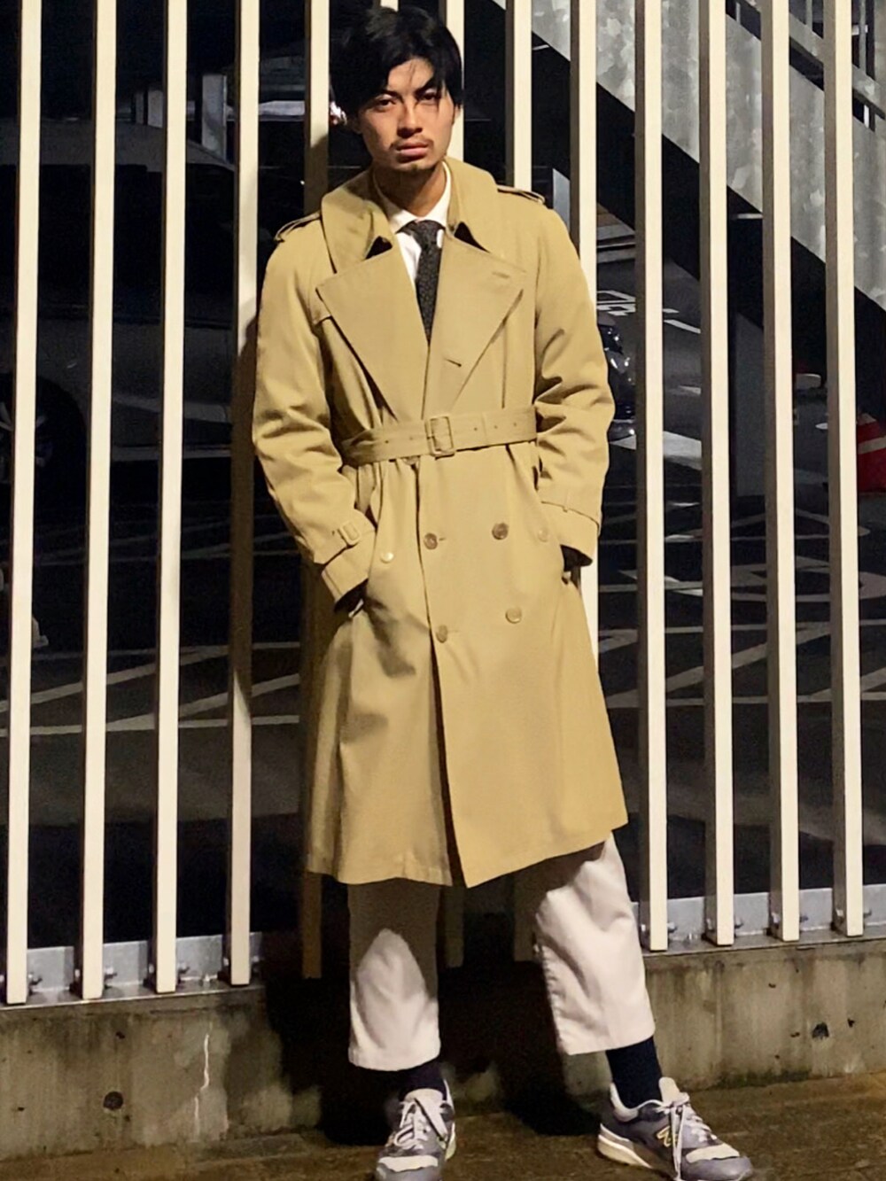 ベージュ系のトレンチコート、ホワイト系のその他パンツ、グレー系のスニーカーを着用したメンズの冬コーディネートの2枚目の写真