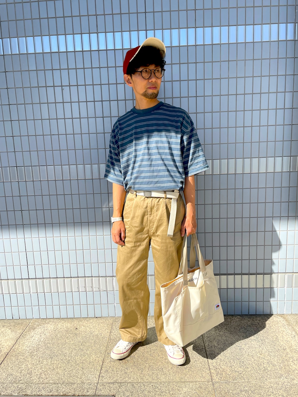 ブルー系のTシャツ/カットソー、ベージュ系のチノパンツ、ホワイト系のトートバッグを着用したメンズの秋コーディネートの2枚目の写真