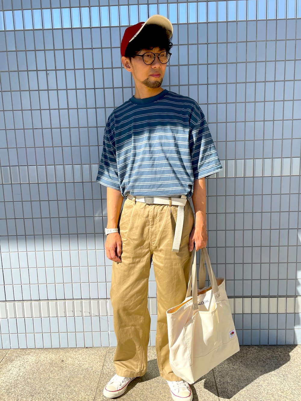 ブルー系のTシャツ/カットソー、ベージュ系のチノパンツ、ホワイト系のトートバッグを着用したメンズの秋コーディネートの3枚目の写真