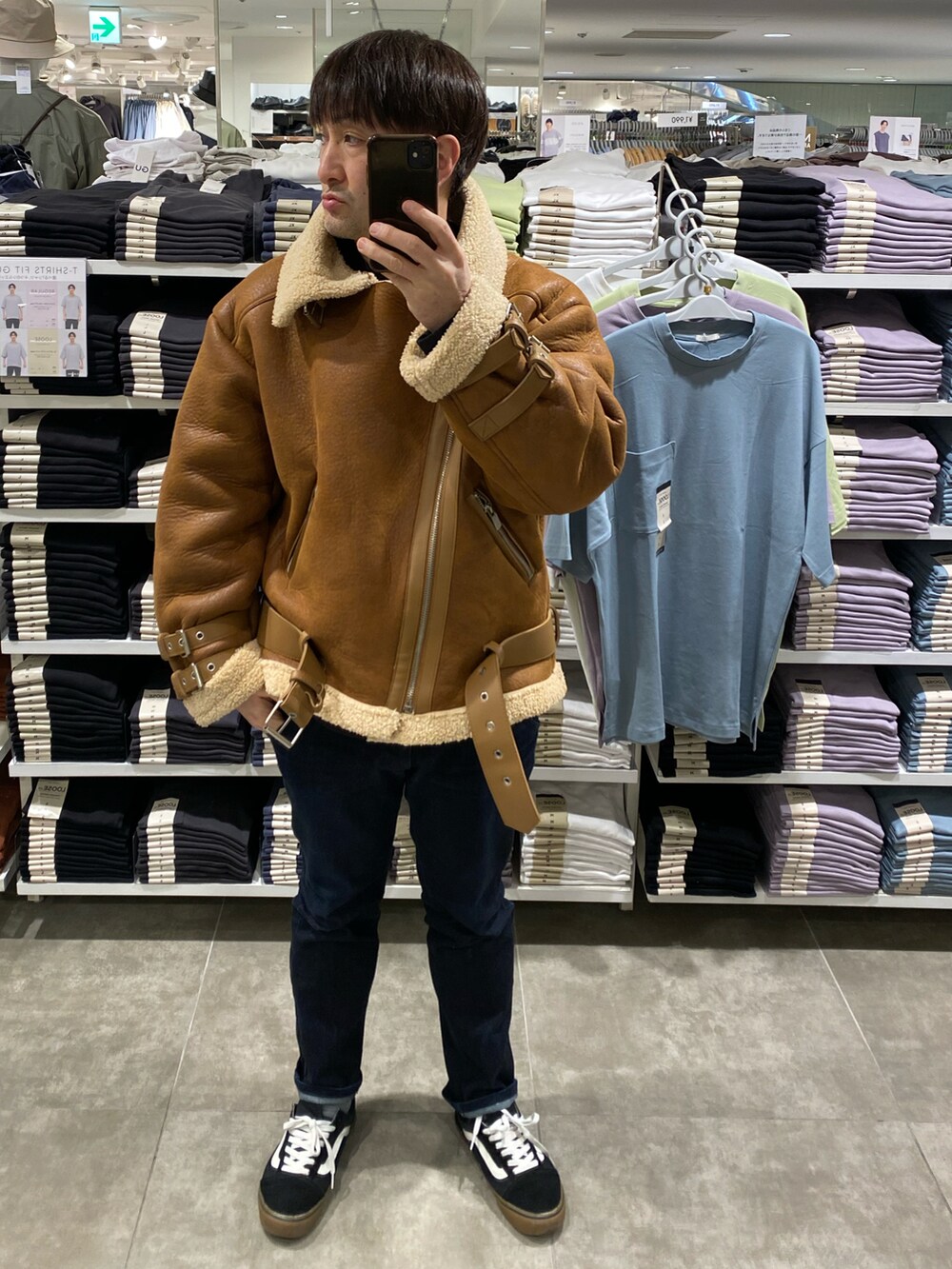 ブラウン系のムートンコート、ブルー系のデニムパンツ、ブラック系のスニーカーを着用したメンズの冬コーディネートの5枚目の写真