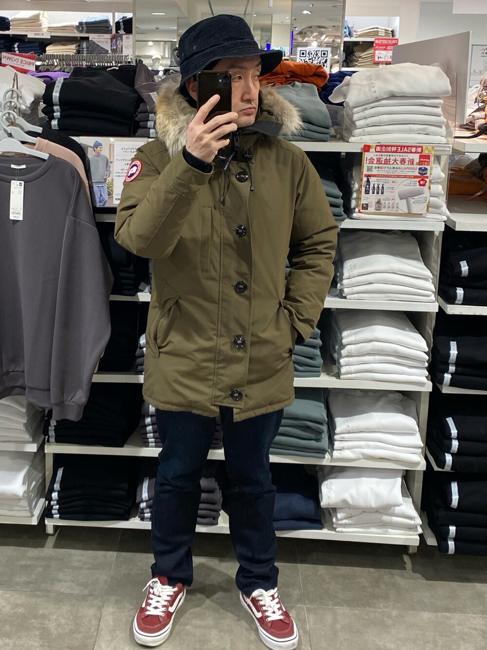 グリーン系のダウンジャケット/コート、ブルー系のデニムパンツ、レッド系のスニーカーを着用したメンズの冬コーディネートの5枚目の写真