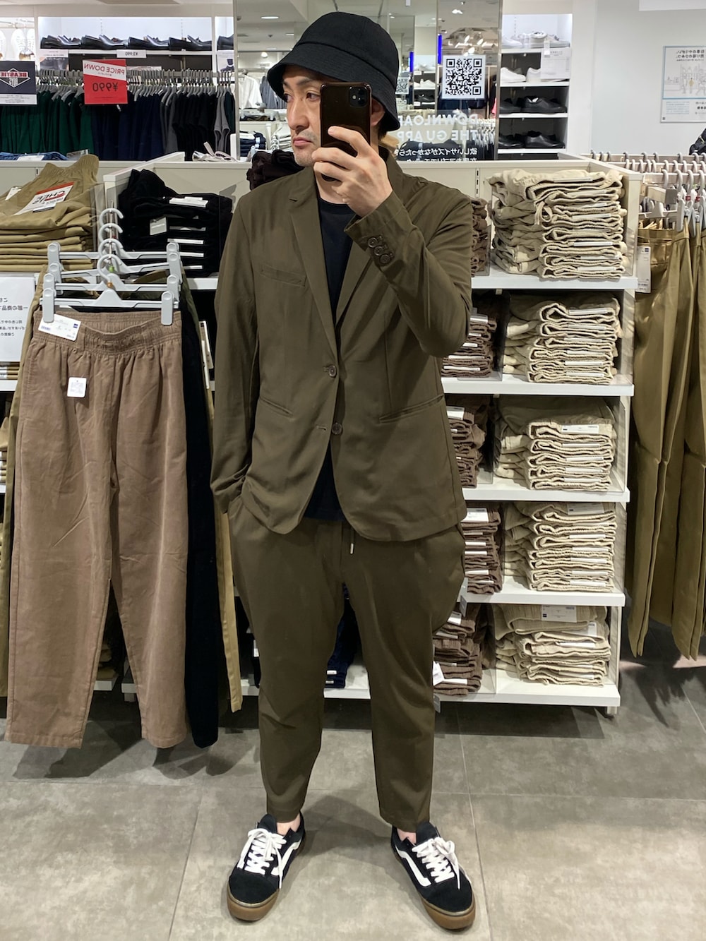 グリーン系のテーラードジャケット、グリーン系のスラックス、ブラック系のスニーカーを着用したメンズの秋コーディネートの2枚目の写真