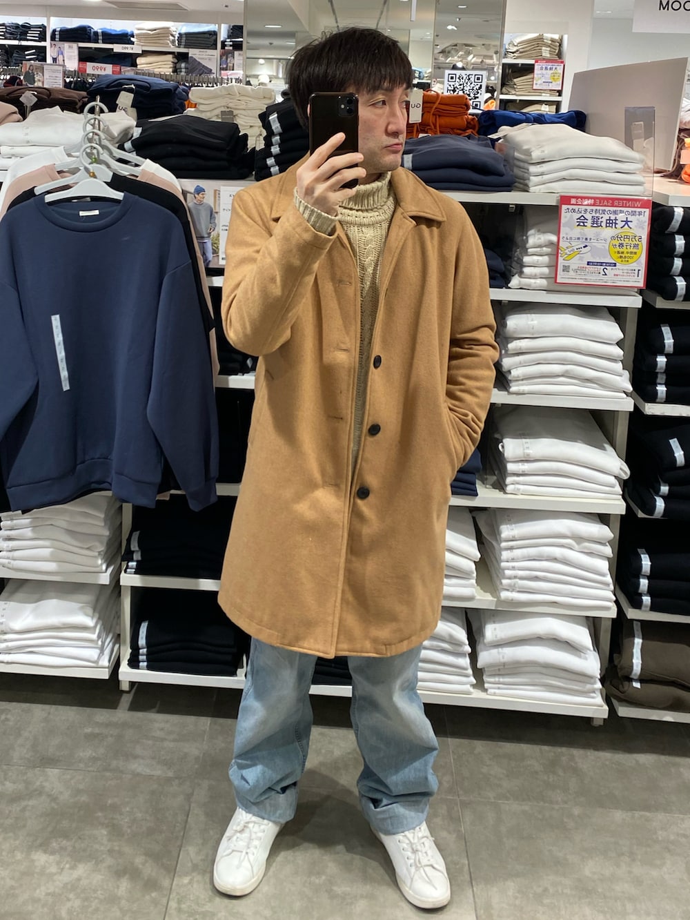 ベージュ系のステンカラーコート、ブルー系のデニムパンツ、ホワイト系のスニーカーを着用したメンズの冬コーディネートの3枚目の写真