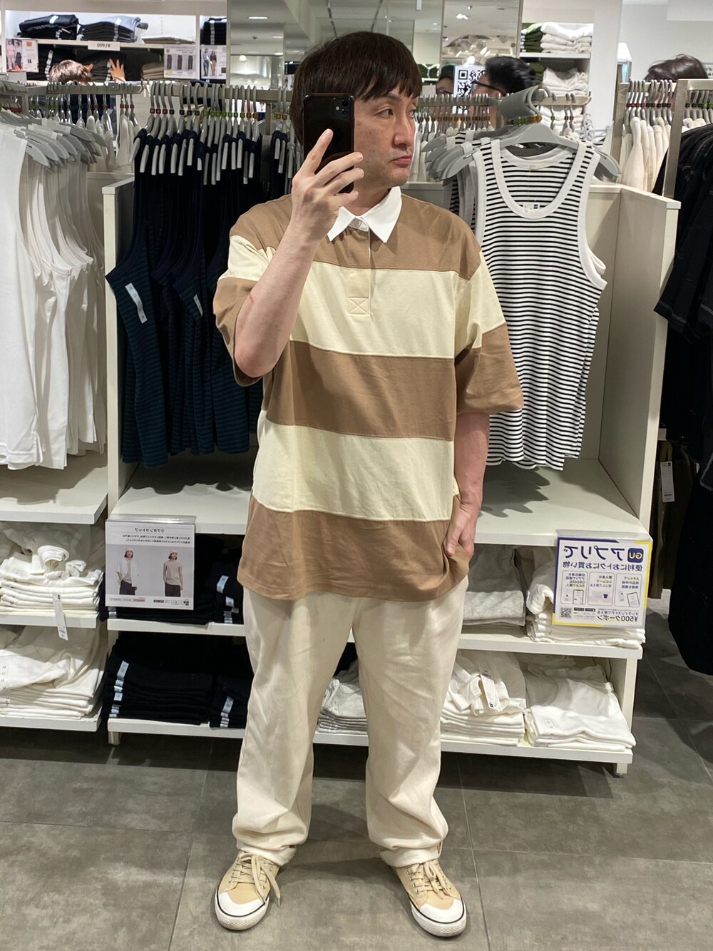 ベージュ系のトップス、ホワイト系のスラックス、ベージュ系のスニーカーを着用したメンズの夏コーディネートの3枚目の写真