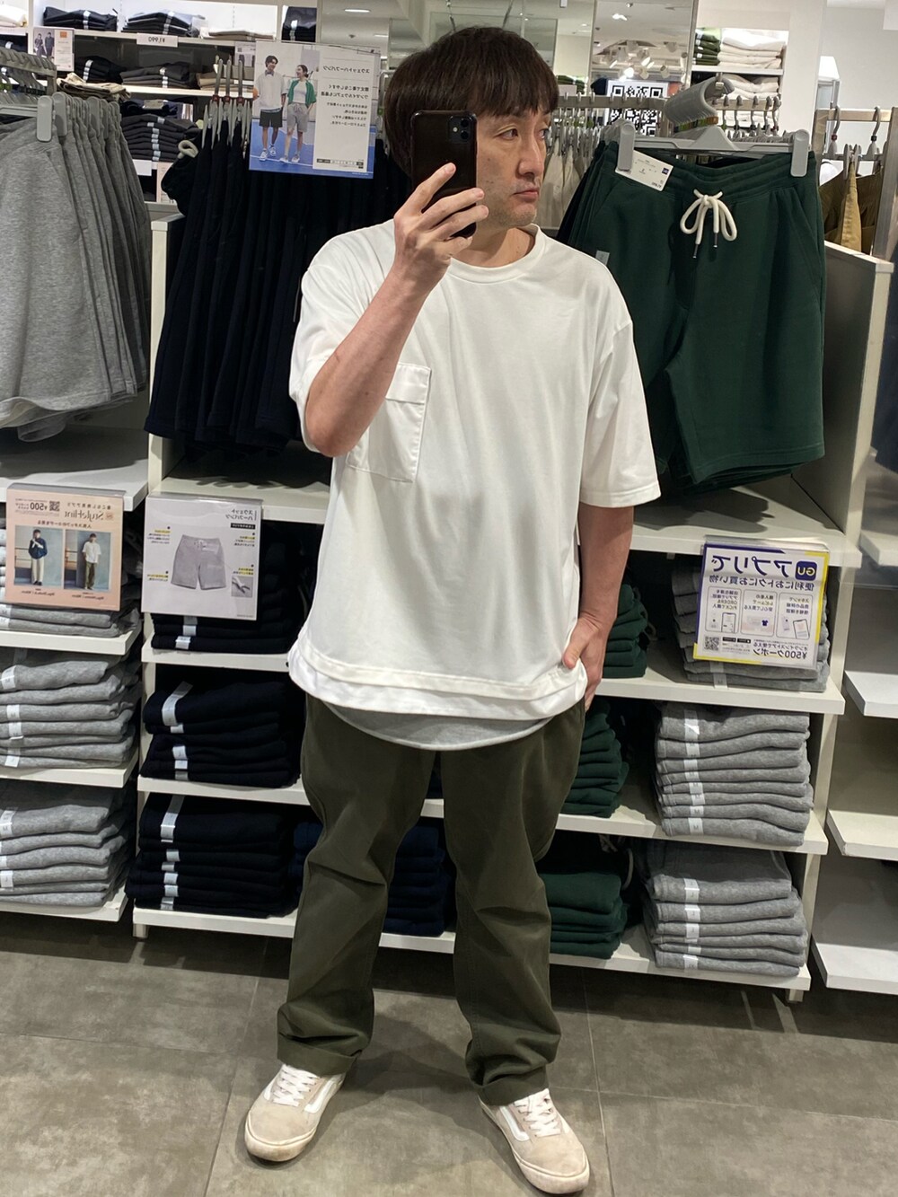 グリーン系のチノパンツ、ベージュ系のスニーカー、ホワイト系のTシャツ/カットソーを着用したメンズの夏コーディネートの3枚目の写真