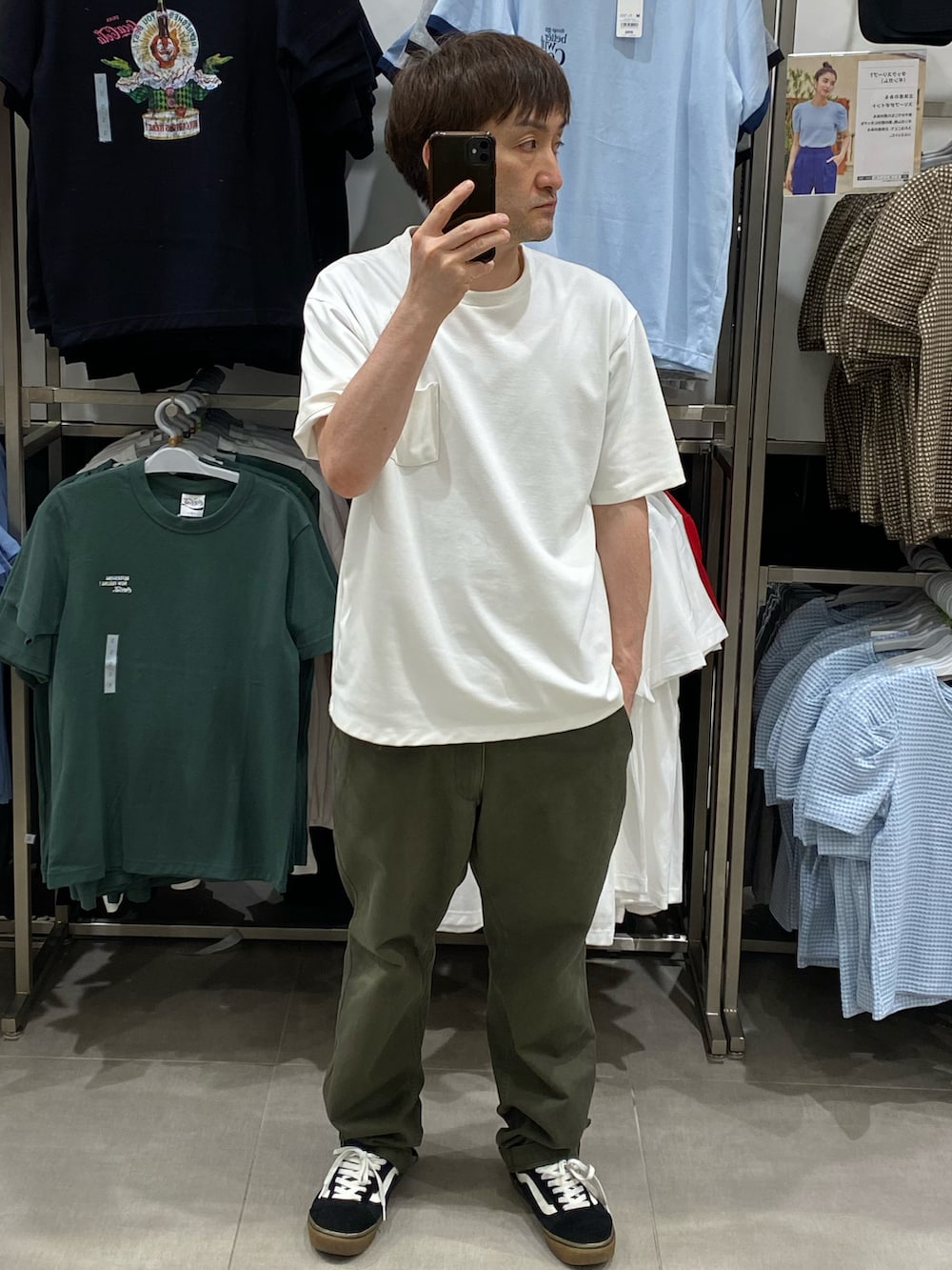 グリーン系のチノパンツ、ホワイト系のTシャツ/カットソー、ブラック系のスニーカーを着用したメンズの夏コーディネートの3枚目の写真