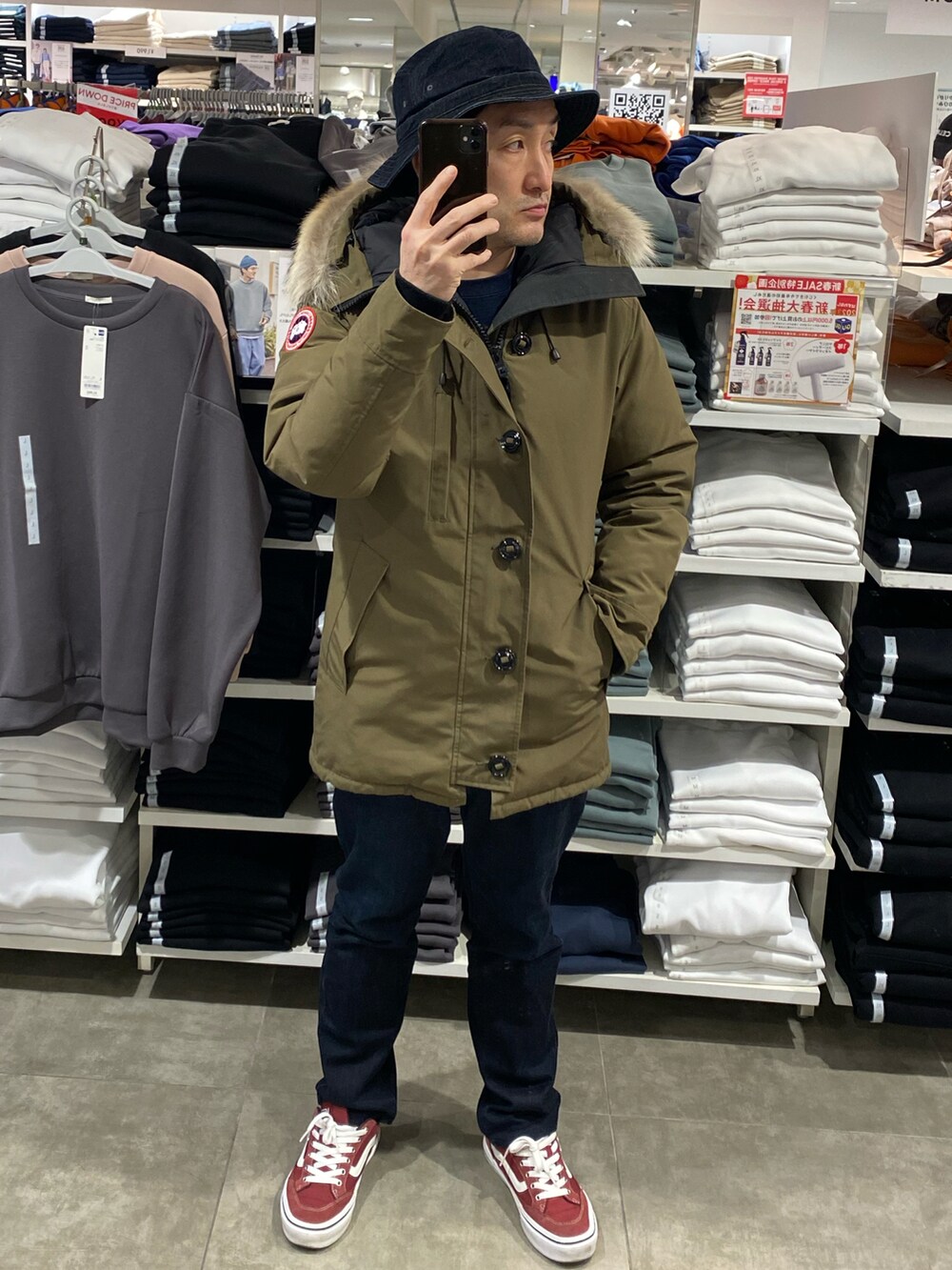 グリーン系のダウンジャケット/コート、ブルー系のデニムパンツ、レッド系のスニーカーを着用したメンズの冬コーディネートの4枚目の写真