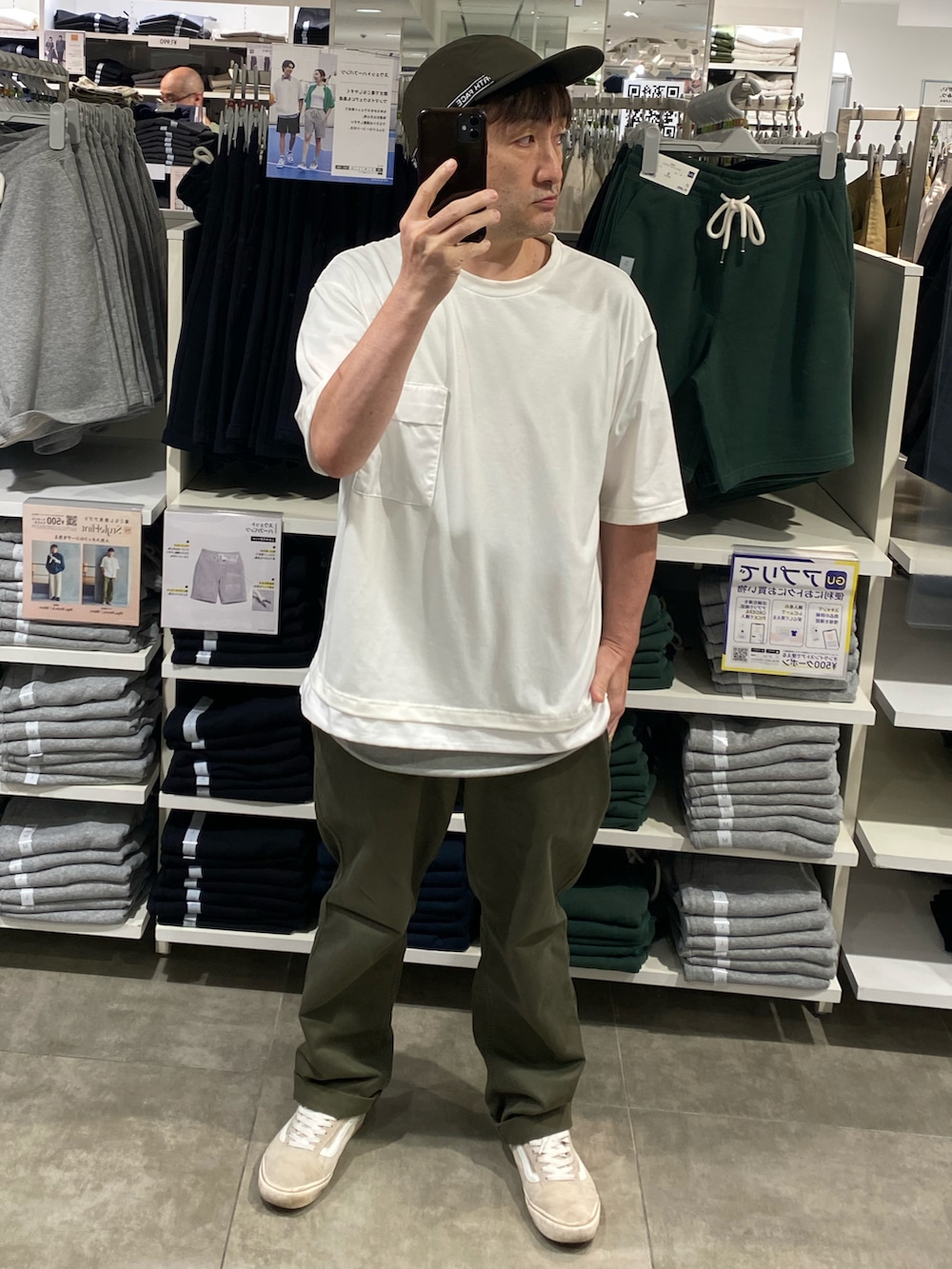 グリーン系のチノパンツ、ベージュ系のスニーカー、ホワイト系のTシャツ/カットソーを着用したメンズの夏コーディネートの2枚目の写真