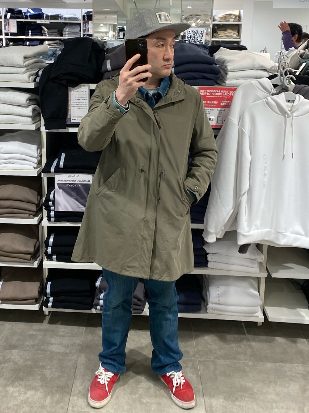 グリーン系のモッズコート、ブルー系のデニムパンツ、レッド系のスニーカーを着用したメンズの春コーディネートの5枚目の写真