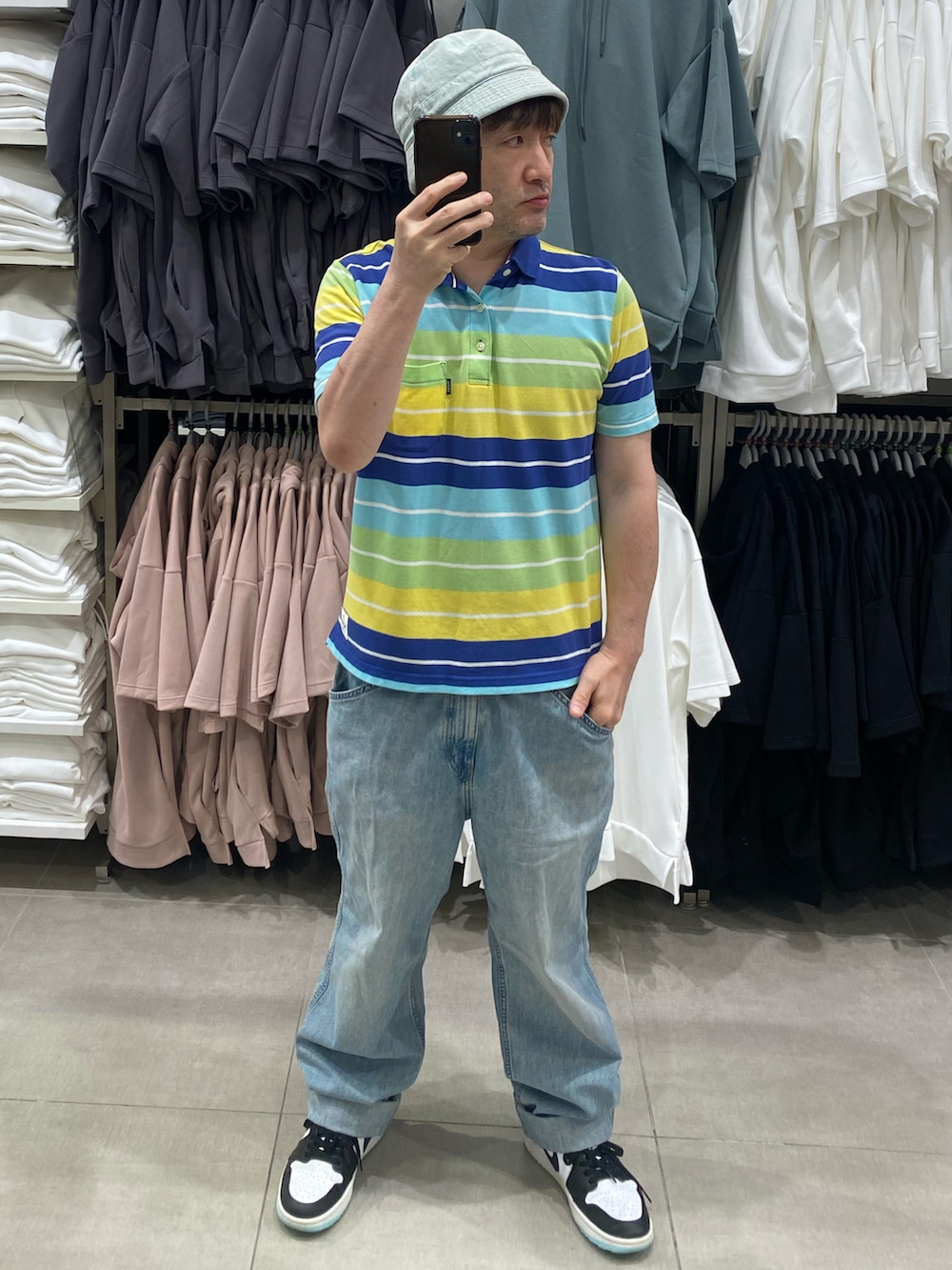 ブルー系のデニムパンツ、ホワイト系のスニーカー、その他のポロシャツを着用したメンズの夏コーディネートの2枚目の写真
