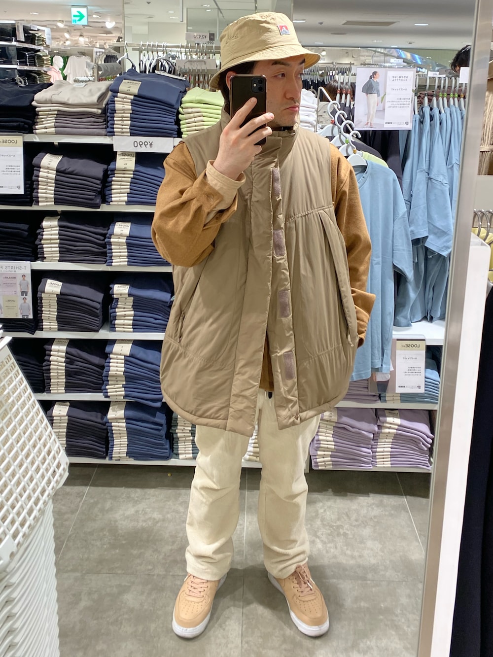 ブラック系のショルダーバッグ、イエロー系のカバーオール、ブラウン系のダウンベストを着用したメンズの春コーディネートの2枚目の写真