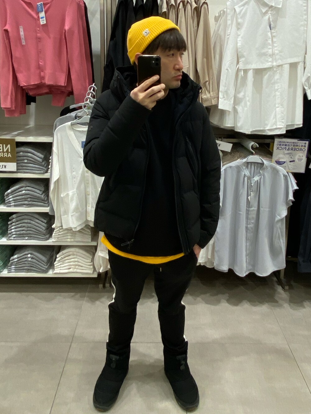 ブラック系のダウンジャケット/コート、ブラック系のスウェット、イエロー系のTシャツ/カットソーを着用したメンズの冬コーディネートの2枚目の写真
